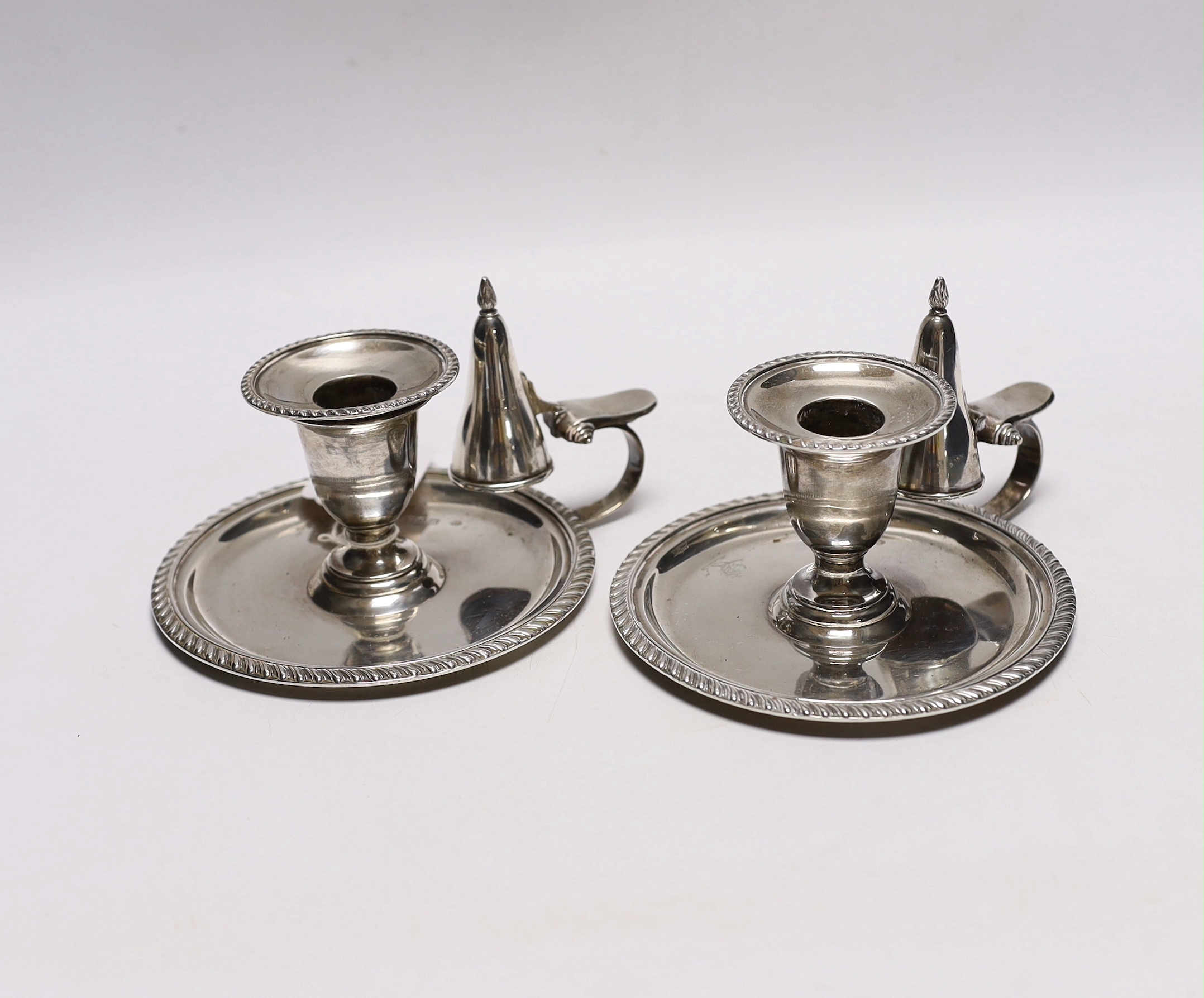 A pair of late Victorian silver chambersticks, with gadrooned borders and matching extinguishers, William Hutton & Sons, London, 1896, base diameter 13.2cm, 18.3oz.